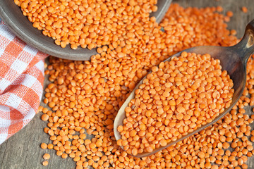 Wall Mural - Dry red lentils in a clay bowl and in a scoop on wooden table