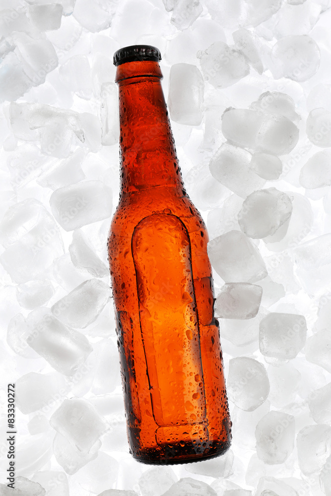 Glass bottle of beer on ice cubes background
