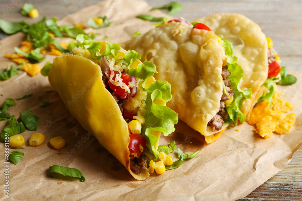 Tasty taco with greens on paper close up