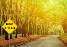 "RISK AHEAD" Sign Against Road In Green Forest - Business Concep