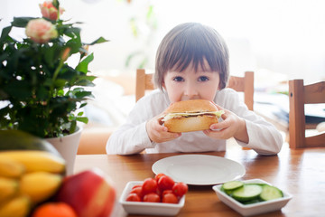 beautiful little boy, eating sandwich at home, vegetables on the