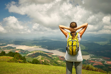 Portrait of happy traveler woman with backpack standing on top o