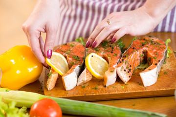 Female hands close up cooking fish in domestic kitchen