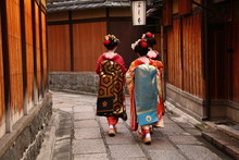 Three Geishas Walking On A Street Of Gion (Kyoto, Japan)