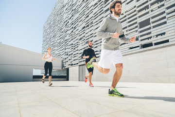 Three young friends running in front of a building