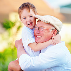 Wall Mural - portrait of happy grandpa and grandson embracing outdoors