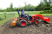 Older Farmer Tilling His Garden With His Compact 4x4 Tractor