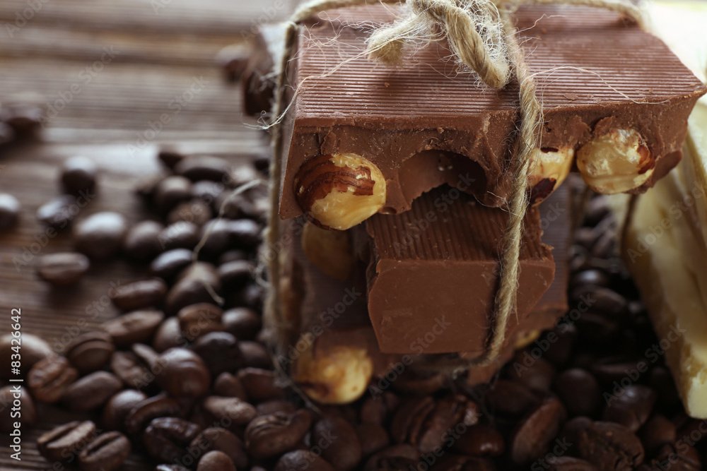 Stack of tied chocolate with coffee beans on wooden table, closeup