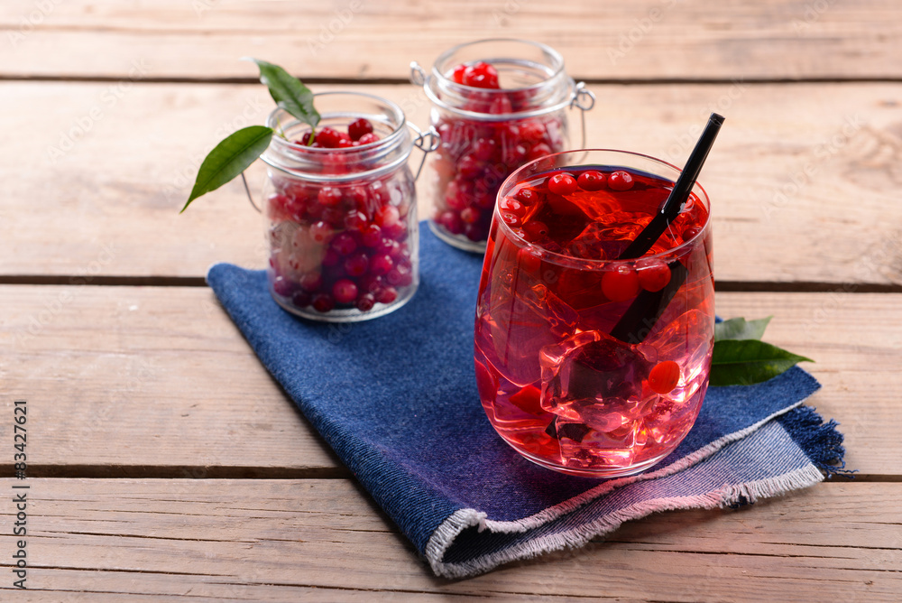 Compote with red currant in glassware on jeans cloth on wooden background