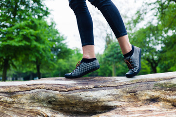 feet of woman walking on tree trunk