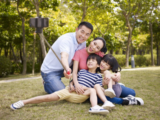 Wall Mural - happy asian family taking a selfie with selfie stick