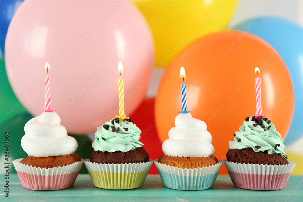 Delicious birthday cupcakes on table on bright background