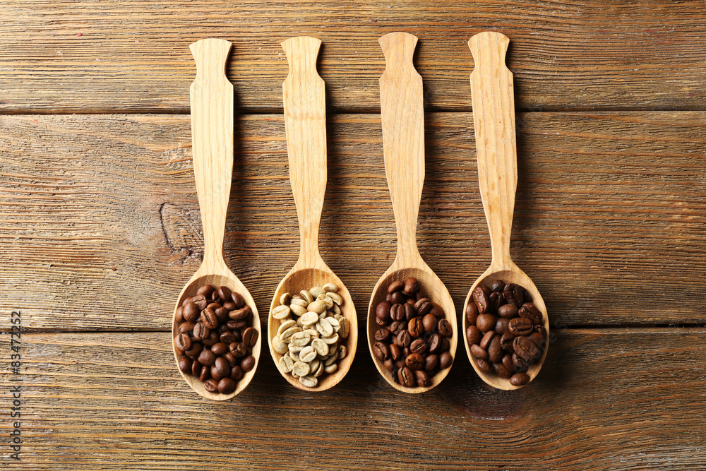 Coffee beans in spoons on wooden background