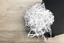 Strips Of Destroyed Paper From Shredder In Trash Can On Wooden Background