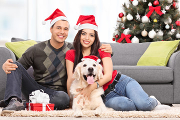 Sticker - Young couple celebrating Christmas with their dog seated at thei