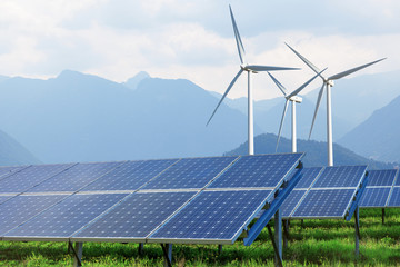 solar panels and wind turbines against mountains