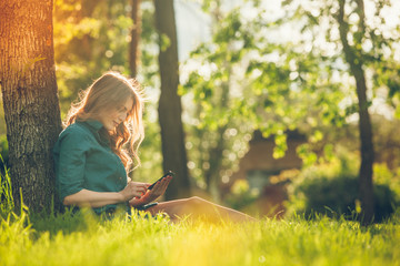 pretty young caucasian woman sitting outside under a tree