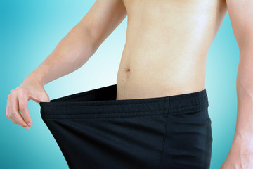 Young man wearing big loose shorts - weight loss concept