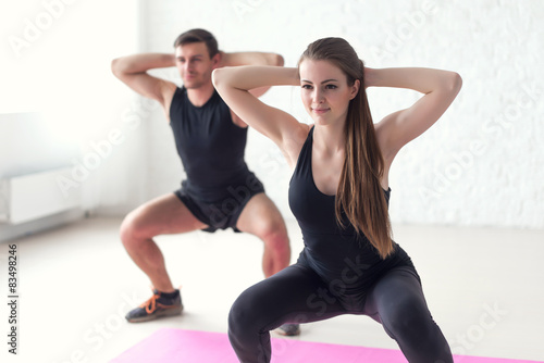 squat exercise. Fitness man and woman exercising squat exercise hands behind
