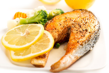 Wall Mural - Grilled salmon and vegetables on white plate warm colors