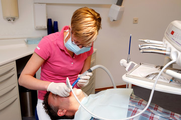 portrait of a young female dental hygienist cleaning the teeth