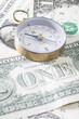 © RooM The Agency - Close-up of a metal compass on a stack of US dollar bills