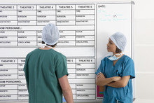 Male And Female Surgeons Looking At Work Rota In Hospital