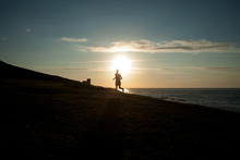 Spain, Galicia, Silhouette Of Man Running On Beach At Sunset