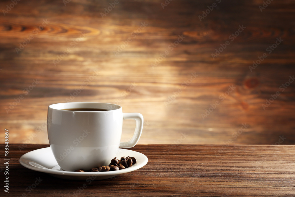 Cup of coffee with grains on wooden background