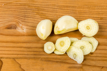 Peeled and sliced garlic cloves on wooden table