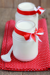 Homemade yogurt in two small glass jars on a wooden table 