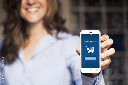 Fotografie, Obraz Shopping cart on the screen. Woman holding her mobile phone.