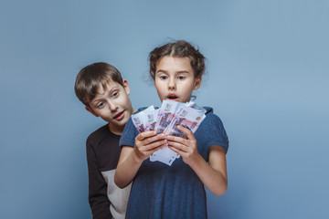 girl holding money bills in the hands of the boy opened his mout