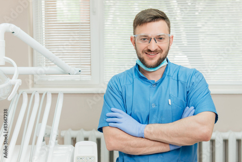 Fototapeta na szkło Portret uśmiechnięty dentysta w stomatologicznym biurze