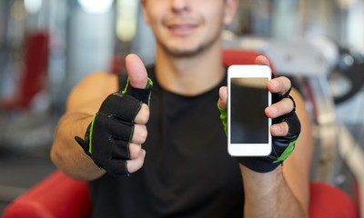 Poster - young man with smartphone showing thumbs up in gym