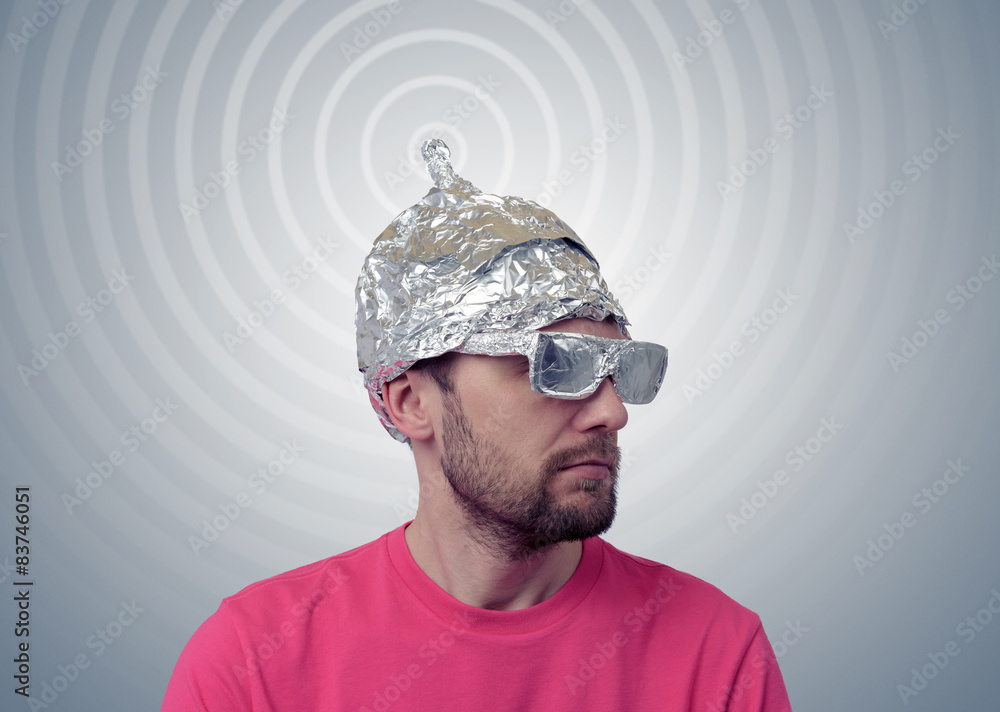 Bearded funny man in a cap of aluminum foil sends signals - obrazy, fototapety, plakaty 