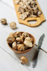 Sliced champignons on board and wooden bowl