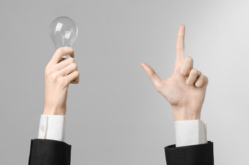 man's hand in a black suit holding a light bulb in studio 