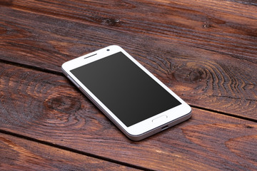 Smart phone with blank screen lying on wooden table