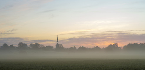 Wall Mural - beautiful, misty sunrise on a field near the village