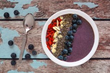 Healthy blueberry smoothie bowl with superfoods on rustic wood