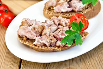 Sandwich with brains and tomato in plate on board