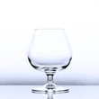 An empty cognac snifter in slightly blue light with a reflection