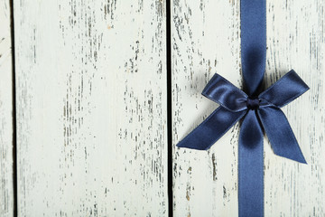 Blue ribbon with bow on white wooden background