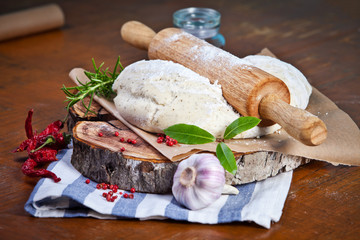 Pizza dough with ingredients on the wooden table