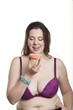 Dicke Frau mit großen Brüsten und Bauchumfang leckt sich die Lippen weil sie einen rosa Erdbeer Donut in der Hand hält