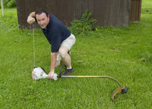 Man Staring A Gas Powered String Trimmer