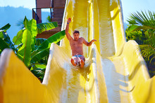 Excited Man Having Fun On Water Slide In Tropical Aqua Park