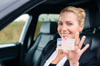 Frau zeigt stolz ihren Führerschein aus dem Auto