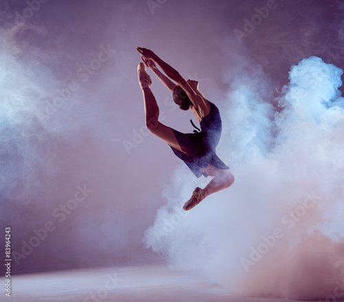 Cuadros en Lienzo Beautiful young ballet dancer jumping on a lilac background.